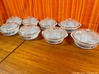 Eight Glasbake casseroles with lids arranged on tabletop