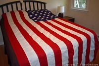 American flag spread out on a bed showing full length and width with red and white stripes and blue canton with stars.