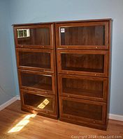 Two identical wooden curio cabinets side by side against a wall