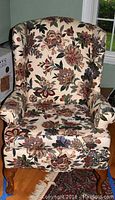 Full front view of cushioned armchair with floral upholstery showing wingback and padded arms.