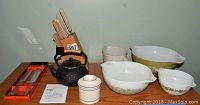 Photo showing Pyrex bowls, stoneware butter keeper, Sotya cast iron tea pot, Farberware knife set in wooden block.