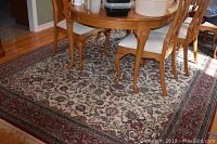 Wide view of the area rug under a wooden dining table with chairs, showing full pattern and colors.