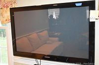 Samsung Series 4 plasma TV showing full screen and frame with sofa reflection visible