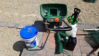 Overall view of the Scotts spreader, sprayer and other accessories placed on ground outside