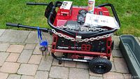Overall view of generator with chain lock, starter fluid, charger box and manual on top