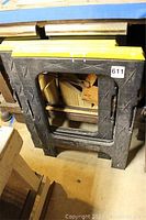 Side view of one black plastic saw horse with yellow edges and cutter marks, showing lot number sticker