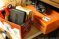 Image showing box containing various drill bits and a black Craftsman case placed beside an orange plastic case labeled 'BOB CARROLL'.