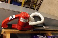 Side view of red and white Little Wonder electric hedge trimmer showing blade and handle details with label.