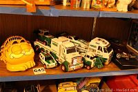 Shelf display of multiple Hess trucks and Garfield phone grouped together showing all collectible items.