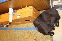 Washer game board lying on its side with three circular holes visible. A black carry bag and rolled up white bean bags are placed nearby.