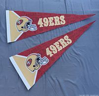 Two red San Francisco 49ers felt pennants laid flat showing full graphics