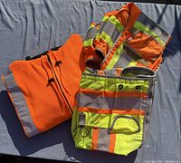 Orange fleece jacket and folded safety vests showing reflective material