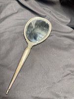 Full view of sterling silver handheld mirror on black background