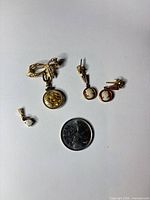 Group shot showing brooch, earrings, opal charm with coin for scale