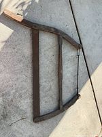 Full view of wooden bow saw lying on concrete