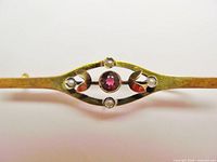 Close-up of brooch showing red stone, seed pearls and gold setting