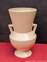Full front view of off-white ceramic vase showing shape and handles