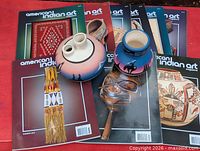 Overview showing two pottery pieces on top of multiple American Indian Art magazines