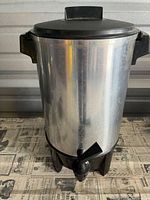 Front view of stainless steel urn showing entire body, lid, handles and base