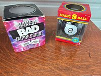 Magic 8 Ball in box and Make A Bad Impression boxed game on tabletop