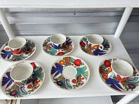 Set of 5 cups and 6 saucers displayed on shelf