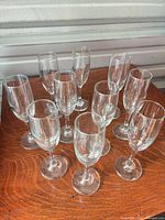 ten clear glass champagne flutes on wooden surface