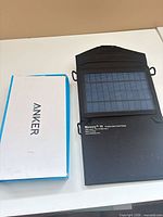 Anker box beside open Instapark Mercury 10 panel showing solar cells and mounting loops