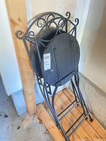 Chairs folded showing metal frame and scrollwork