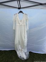 Full view of ivory wedding dress on hanger showing length and train