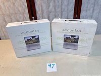 Front view of two Accurian DVD player boxes