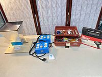 Overall lot view: grain mill, two blue power boxes, toolbox of hand tools, Weller kit