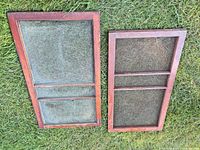Both wooden framed screens lying on grass, front view
