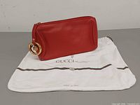 front view of red Gucci pouch on white dust bag