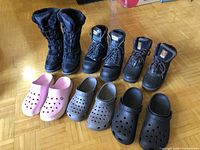 Full set of three boot pairs and three Crocs pairs on floor