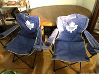 Two unfolded blue Coleman Toronto Maple Leafs camp chairs side by side showing logos, cup holders, frames and overall condition