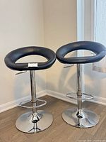 Full view of both black bar stools with chrome bases