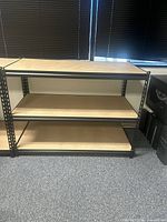 Front view of assembled black metal shelving unit with three MDF shelves
