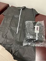 Unpacked gray coverall laid flat beside sealed 5-pack