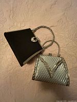 Silver purse and black clutch flat lay showing overall designs