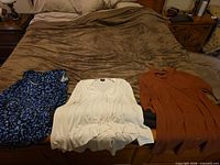Three tops laid out on bed