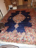 Full view of the wool Kirman rug showing dark blue center medallion and floral border.