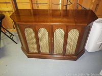 Front view of closed wood veneer stereo console with lattice speaker grilles