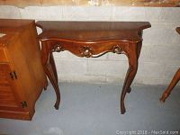 Full view of the wood table made in Italy, showing the curved sides, floral carvings on apron, and cabriole legs next to cabinetry.
