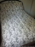 Full view of the double bed made up with the floral duvet cover and two matching pillowcases on a dark bed frame.