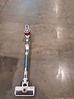 Full view of assembled cordless stick vacuum lying on floor