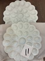 Two white porcelain egg platters showing overall design and wells
