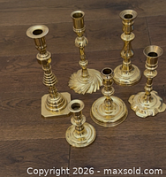 All six assorted brass candlestick holders displayed on wooden surface