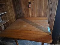 Table with one leaf raised, showing top surface and wood grain