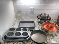 Overview of all bakeware, mixing bowls and cooling rack on counter