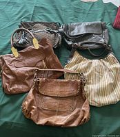 Five handbags laid out on surface